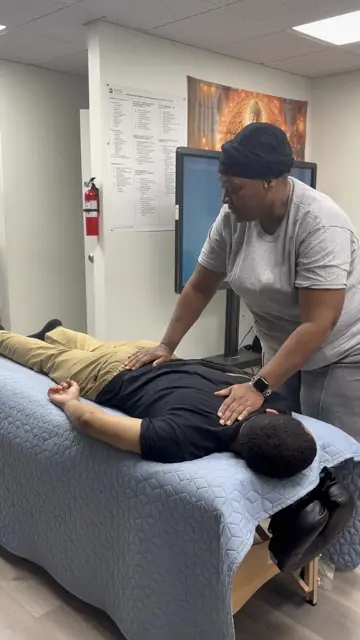 An AMOM learner practicing massage on a covered treatment table