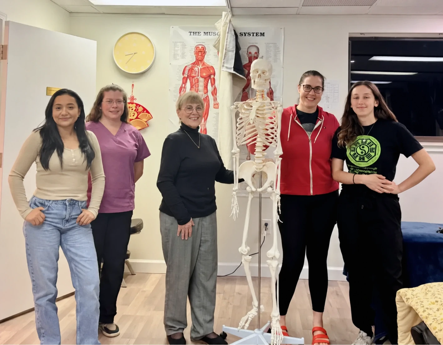 Five members of the AMOM school community gathered around an anatomy model in the classroom